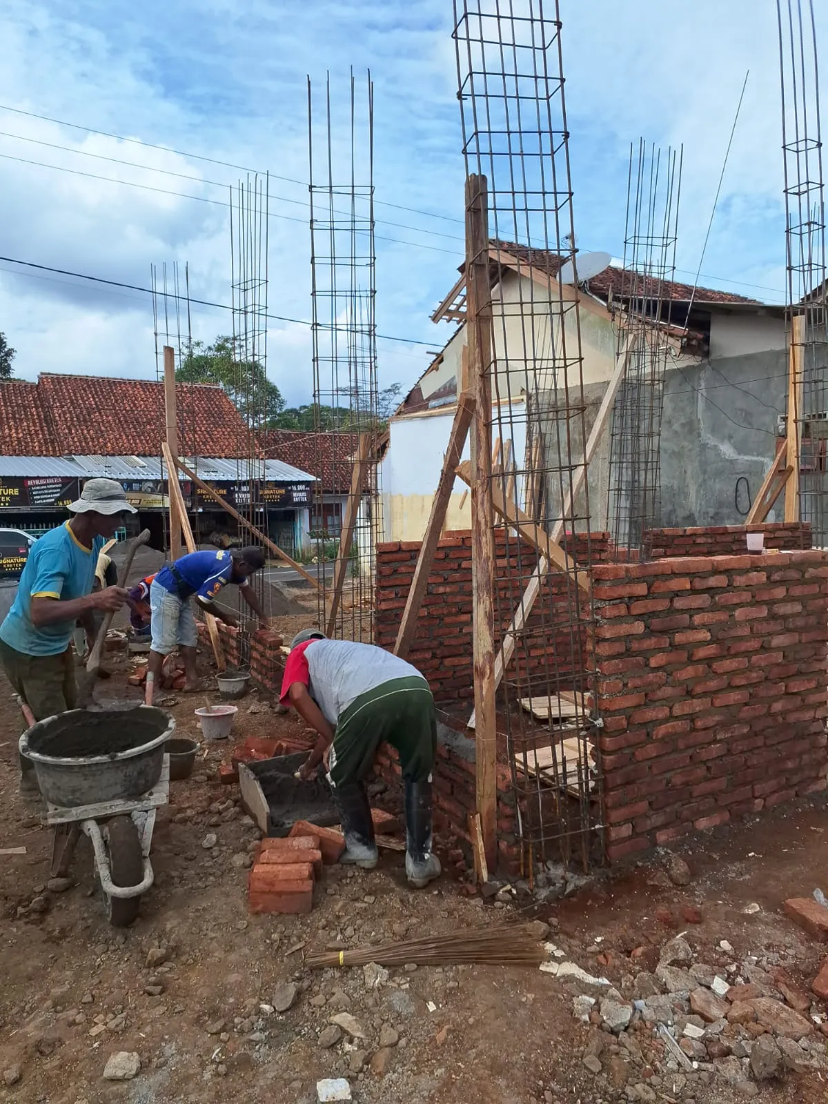 Pekerja memasang dinding bata merah di antara kolom besi