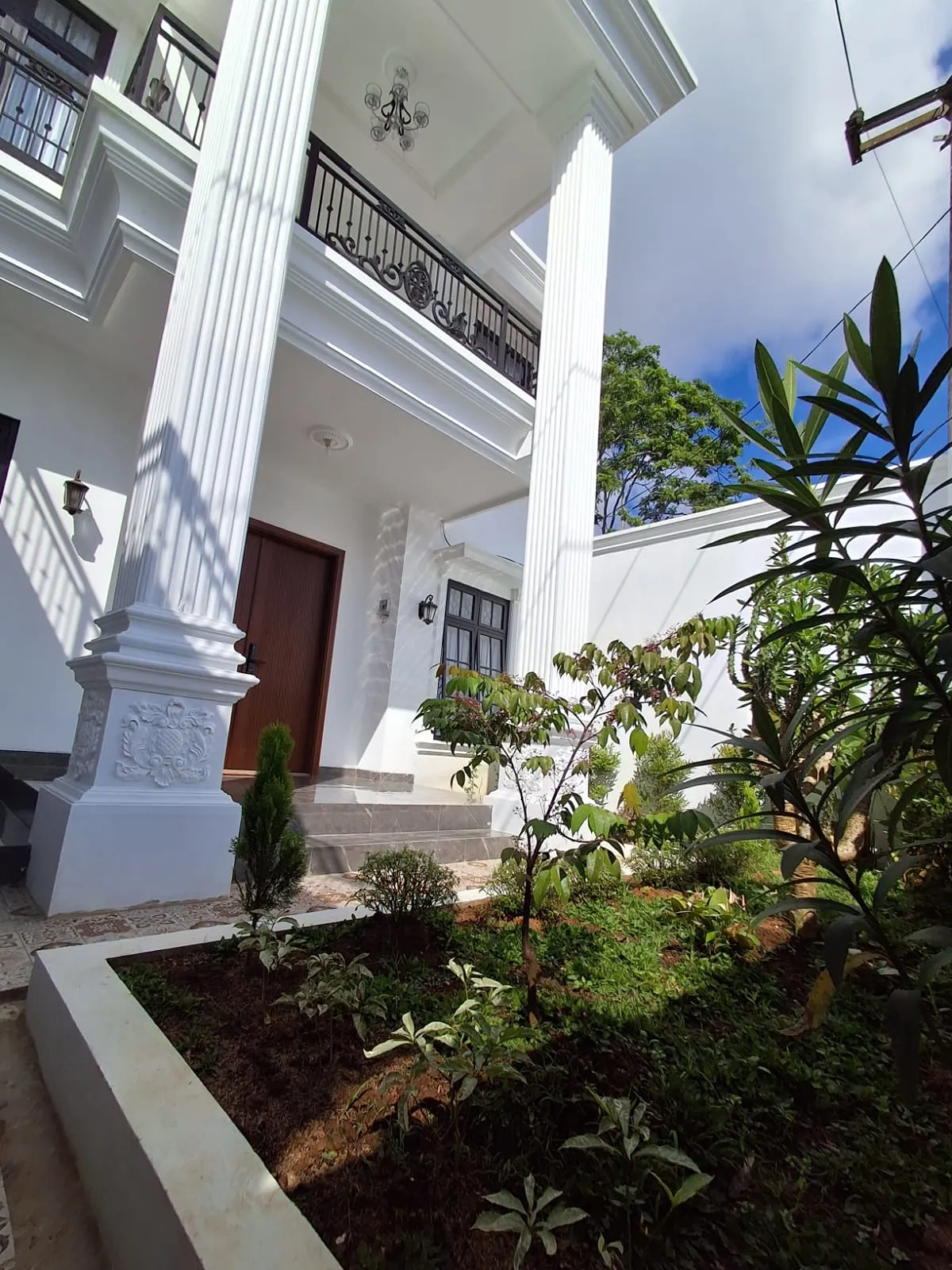 Teras rumah dengan kolom klasik dan taman setelah renovasi