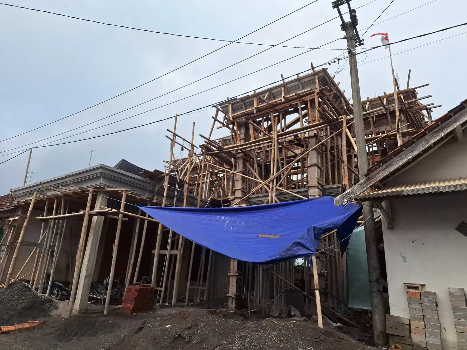 Rangka bangunan bertingkat dengan perancah bambu dan terpal pelindung